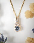 Gold necklace with a blue gemstone pendant on a white background