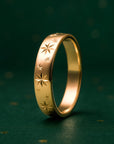 Gold ring with star patterns on a dark green background