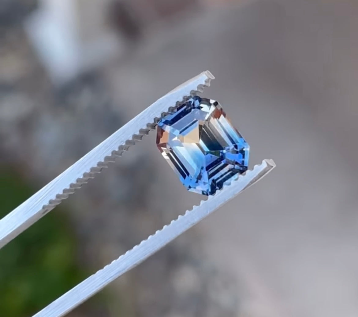 an emerald cut blue and peach parti sapphire