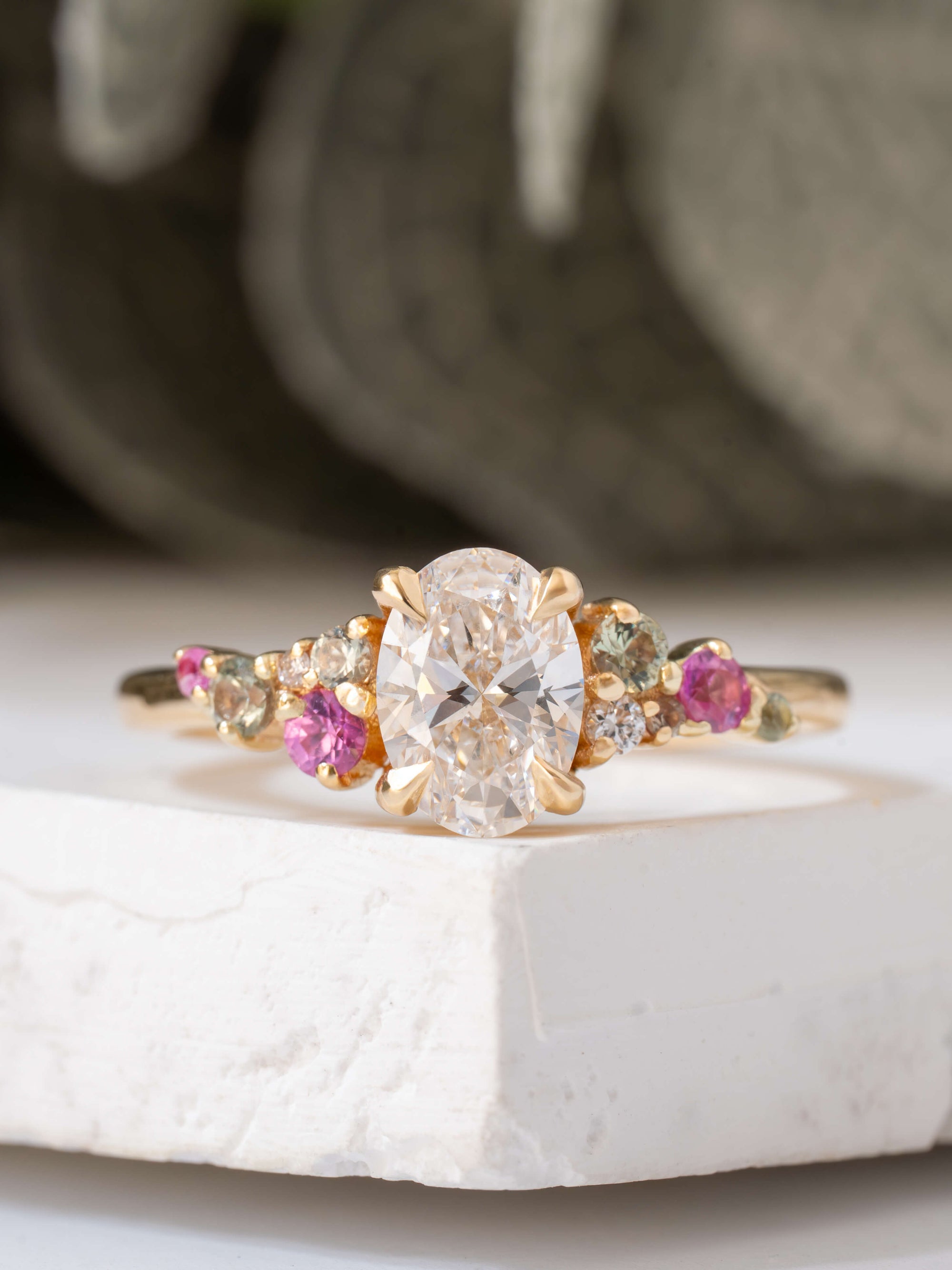 Gold ring with a central diamond and pink gemstones on a white surface