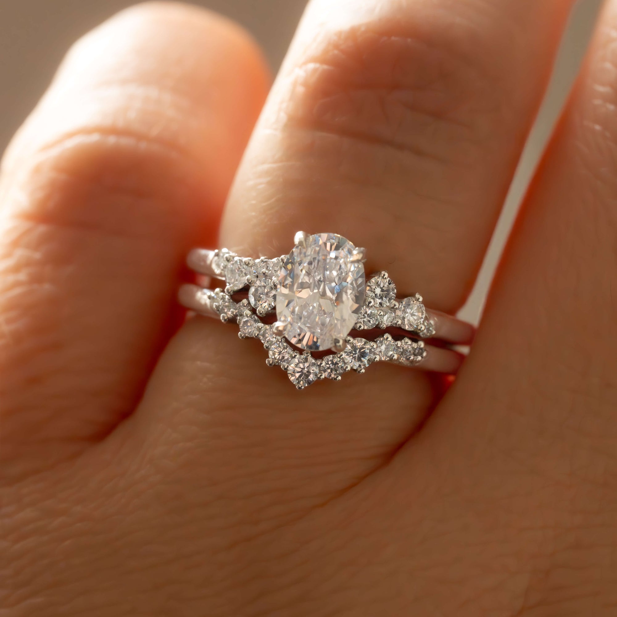 Close-up of a hand wearing a diamond ring with a pear-shaped center stone.