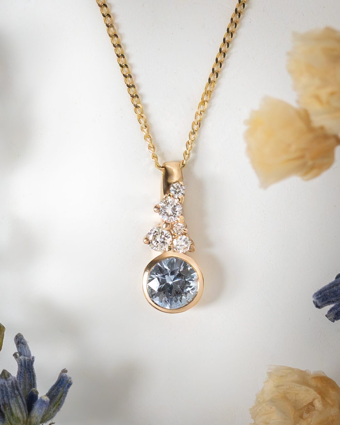Gold necklace with a blue gemstone pendant on a white background