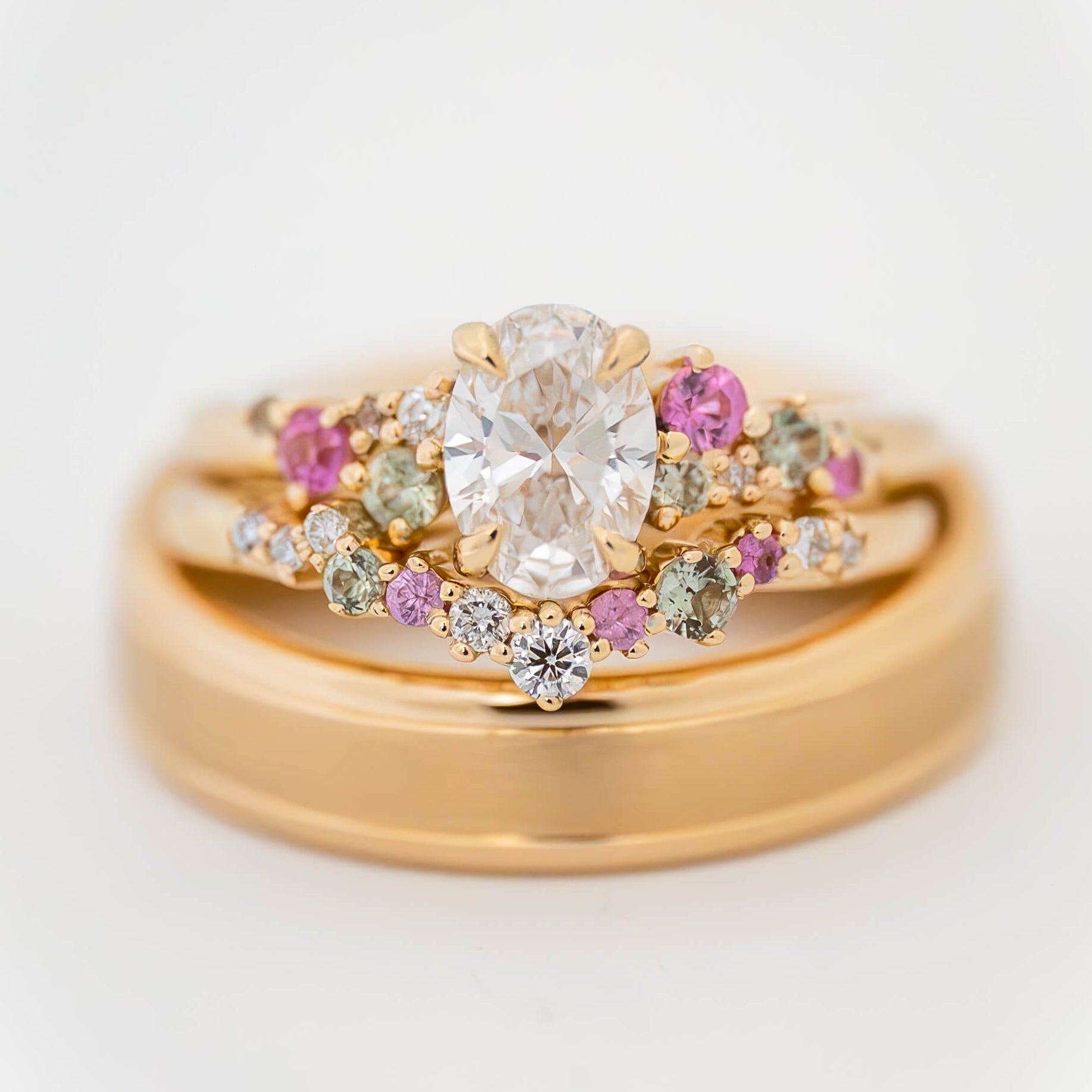 Gold ring with diamonds and pink gemstones on a white background