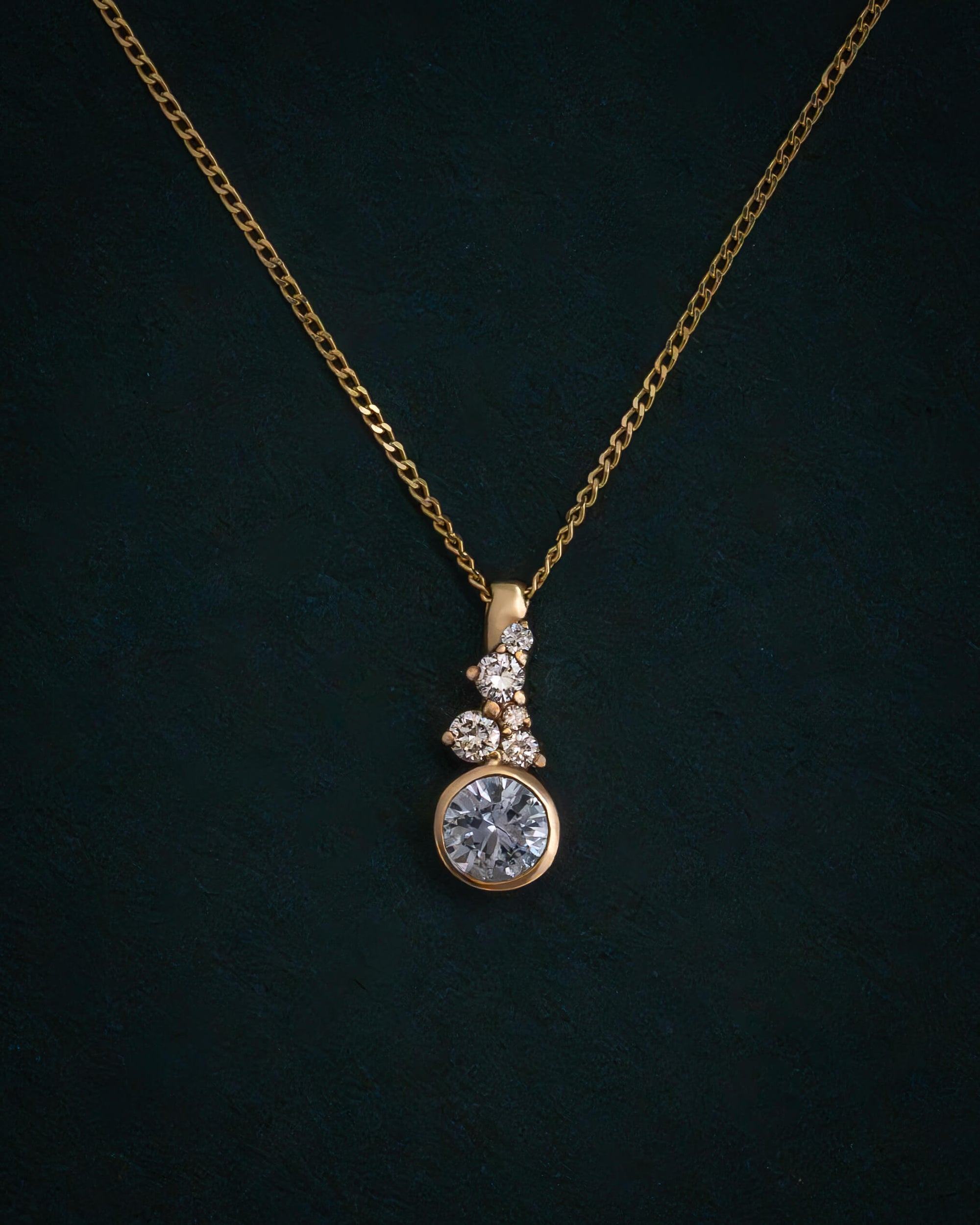 Gold necklace with a diamond pendant on a dark background